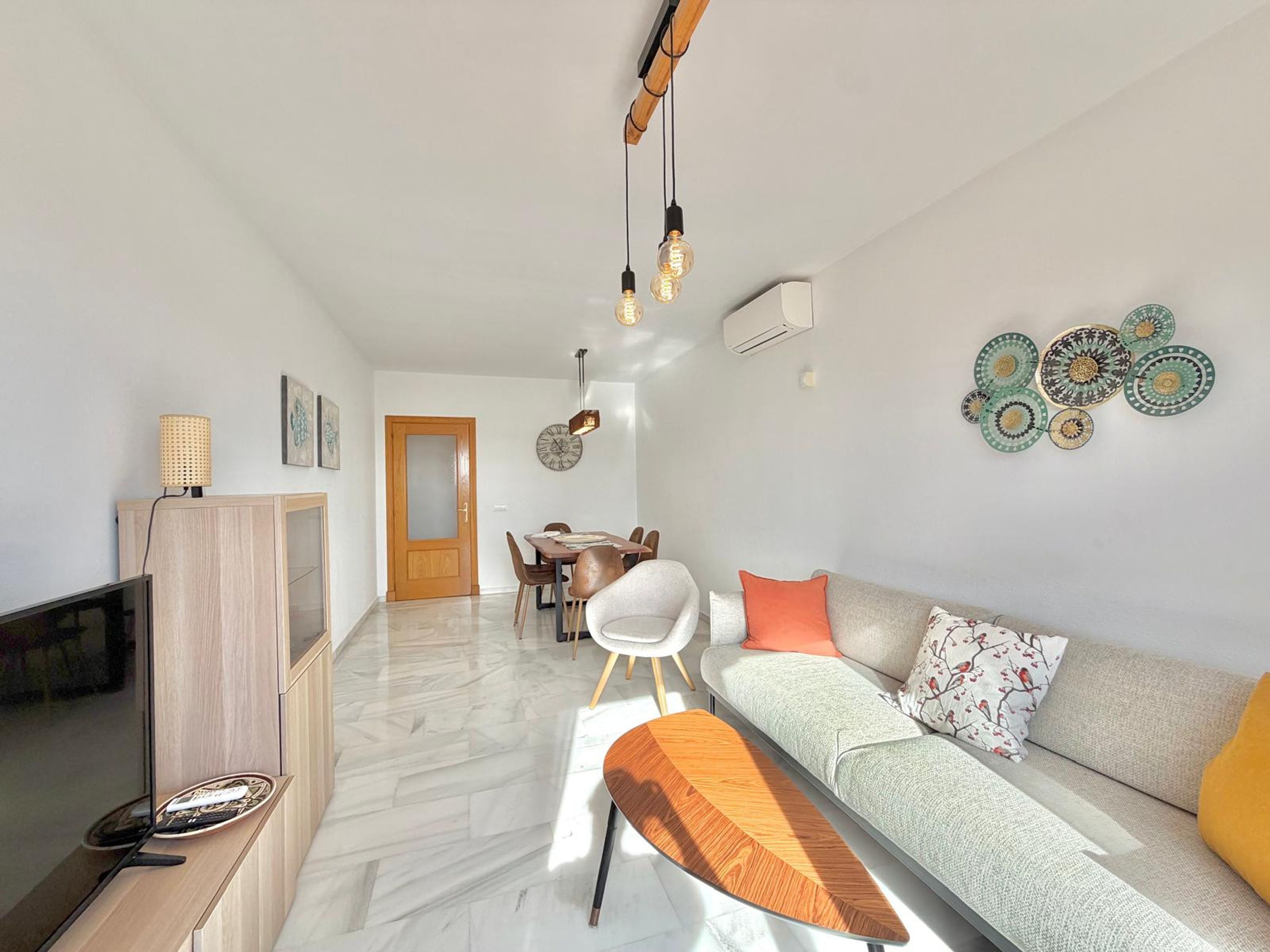 A modern living room with a sofa, coffee table, and dining area.