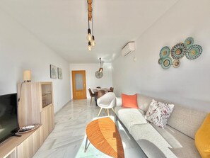 Una sala moderna con televisor, sofá y comedor.