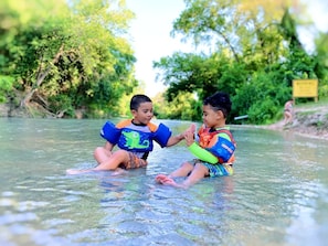 Zwei Kinder planschen im seichten Wasser.