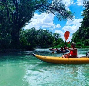 A person kayaking on a river surrounded by lush greenery.