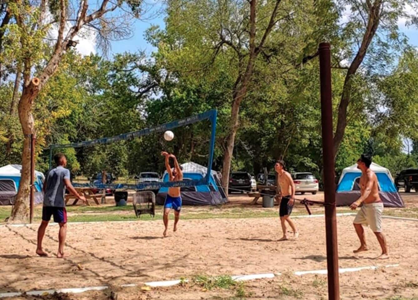 Un camp de voleibol de sorra amb tendes al fons.