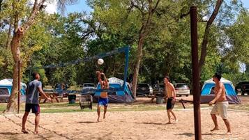 Un camp de voleibol de sorra amb tendes al fons.