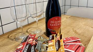 A bottle of wine, two glasses, and assorted chocolate bars on a wooden board.