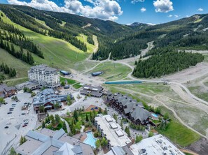 Ein Skigebiet mit einem großen Gebäude, einem Parkplatz und einem Schwimmbad.