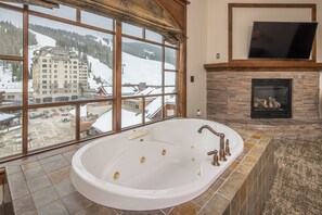 Eine große Badewanne mit Blick auf einen Skiort durch große Fenster.