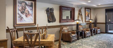 A room with a wooden table and chairs, a brown leather sofa, and framed artwork on the walls.