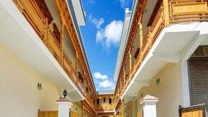 A corridor with wooden doors, a central open space, and a clear blue sky above. - Hotel Dimbir Regency (Leh)