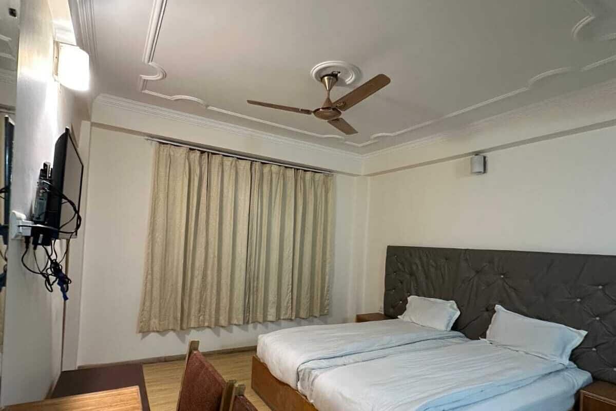 A bedroom with two beds, a ceiling fan, a TV, and a dining table.