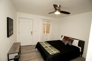 Ein Schlafzimmer mit einem Bett, einem Schreibtisch, einem Deckenventilator und einem Fenster.