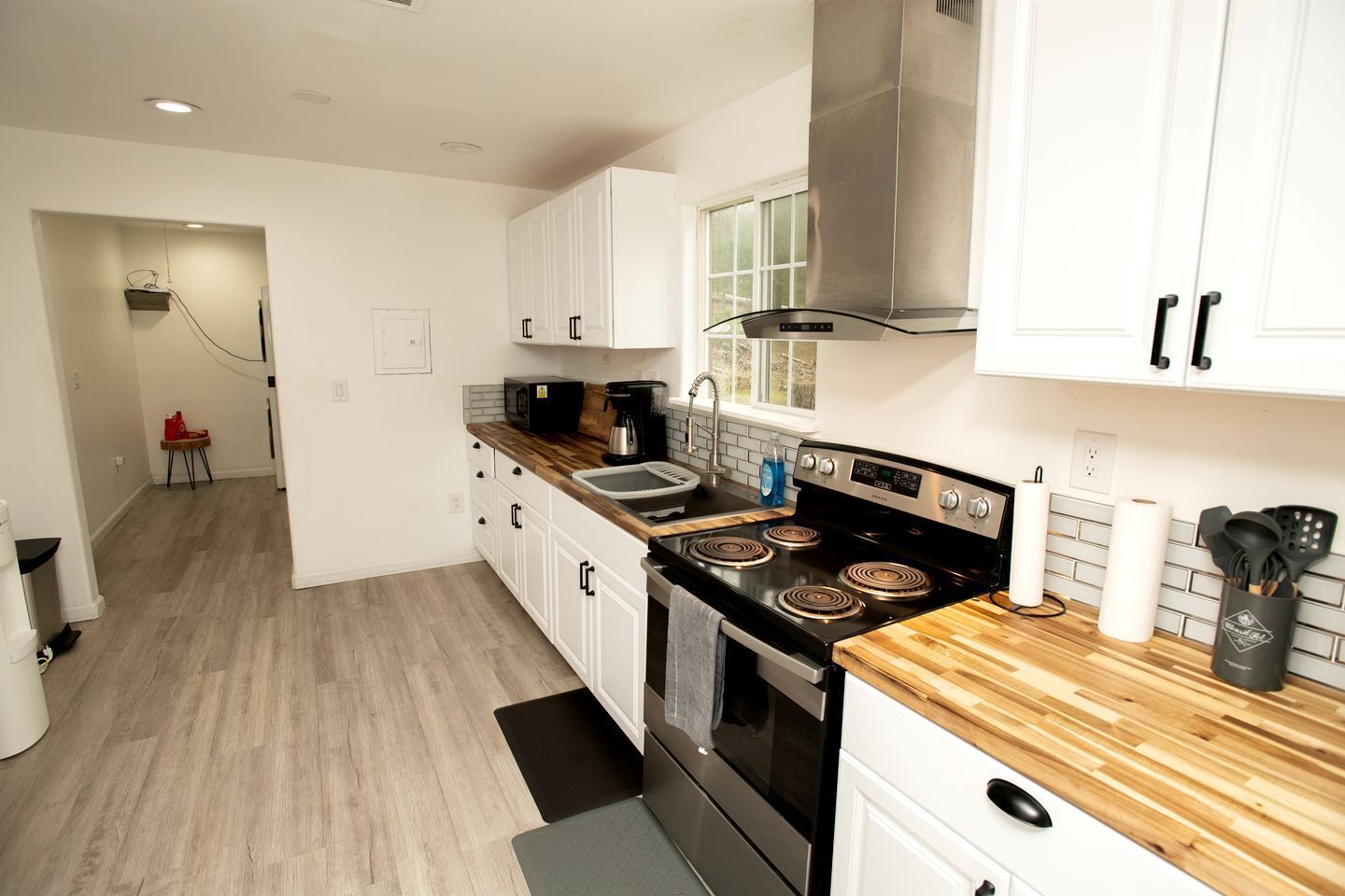 Une cuisine moderne avec des armoires blanches, une cuisinière noire et un plan de travail en bois.