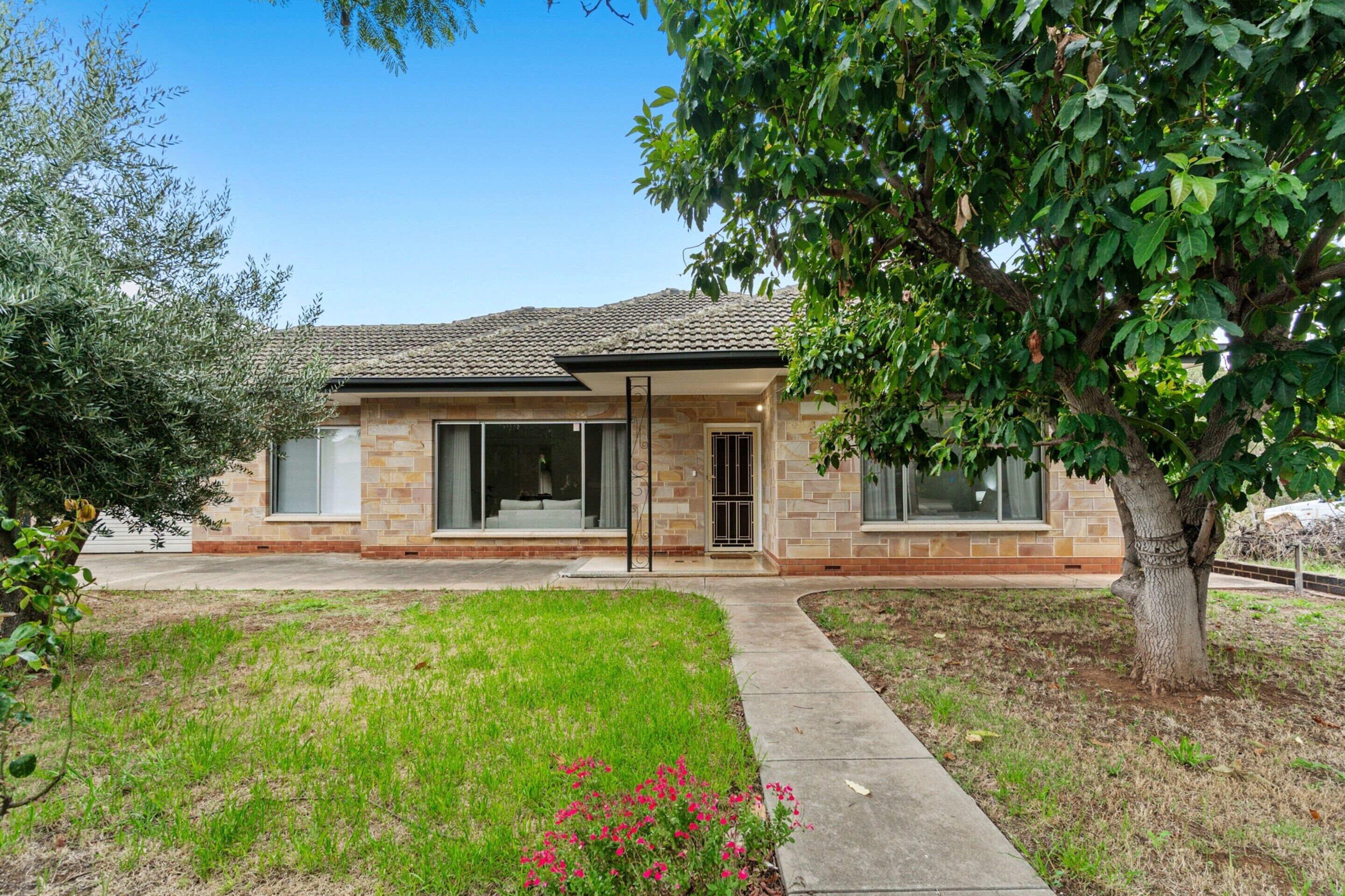 A two-story house with a stone facade, large windows, and a tree in the front yard.
