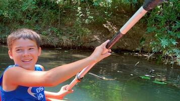 A person in a canoe on a river surrounded by greenery.