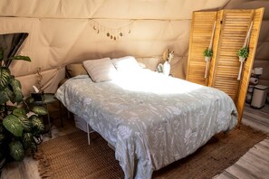 A tented room with a bed, a small table with a plant, and a wooden wardrobe. - Tranquil Desert Retreat in a Geodesic Dome with Scenic Views in Las Vegas, Nevada (Las Vegas)
