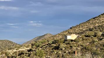 A mountainous landscape with sparse vegetation and a small building on a hill.