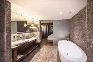 A modern bathroom with a double sink, a bathtub, and a large mirror. - Hotel Das Sonnreich (Bad Loipersdorf)