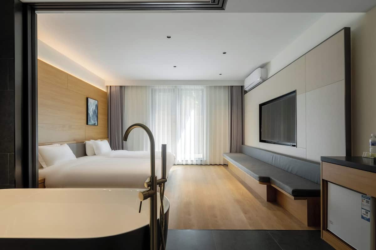 Une chambre d’hôtel moderne équipée d’un lit, d’un bureau, d’une télévision et d’un coin salon.