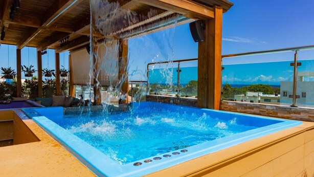 A hot tub with water jets, a wooden deck, and a view of the ocean. - Luxurious 3-bedroom Apartment With Private Balcony in Puerto Plata (Puerto Plata)