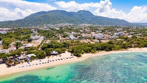 A coastal town with a beach, clear turquoise waters, and a mountainous backdrop. - Luxurious 3-bedroom Apartment With Private Balcony in Puerto Plata (Puerto Plata)