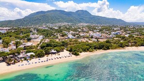 A coastal town with a beach, clear turquoise waters, and a mountainous backdrop. - Luxurious 3-bedroom Apartment With Private Balcony in Puerto Plata (Puerto Plata)