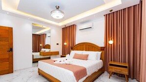 A modern bedroom with a large bed, wooden headboard, a bedside table, a mirror, and a ceiling light fixture. - Luxurious 3-bedroom Apartment With Private Balcony in Puerto Plata (Puerto Plata)