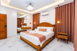 A modern bedroom with a large bed, wooden headboard, a bedside table, a mirror, and a ceiling light fixture. - Luxurious 3-bedroom Apartment With Private Balcony in Puerto Plata (Puerto Plata)