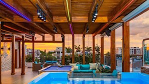A rooftop pool area with a wooden ceiling, lounge seating, and a view of the cityscape at sunset. - Luxurious 3-bedroom Apartment With Private Balcony in Puerto Plata (Puerto Plata)