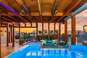 A rooftop pool area with a wooden ceiling, lounge seating, and a view of the cityscape at sunset. - Luxurious 3-bedroom Apartment With Private Balcony in Puerto Plata (Puerto Plata)