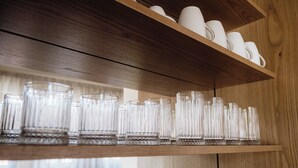 A wooden shelf with multiple clear glasses and white cups. - Galetso Stone Studio by Still Collection (Νικήτη)