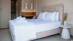 A modern bedroom with a large bed, a bedside table with a vase, and a wooden headboard. - Galetso Stone Studio by Still Collection (Νικ ήτη)