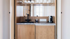 A kitchen with wooden cabinets, a countertop, and a coffee machine. - Galetso Stone Studio by Still Collection (Νικήτη)