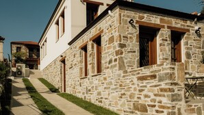 A stone building with a paved pathway leading to a wooden door. - Galetso Stone Studio by Still Collection (Νικήτη)