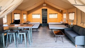 A tented accommodation with a central table, bar stools, a sofa, and a bed. - Texas Safari Tent Adventures Await in this Lovely San Marcos River Rental (Kingsbury)
