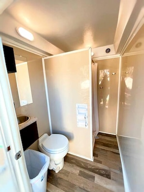 A compact bathroom with a toilet, sink, and mirror. - Texas Safari Tent Adventures Await in this Lovely San Marcos River Rental (Kingsbury)