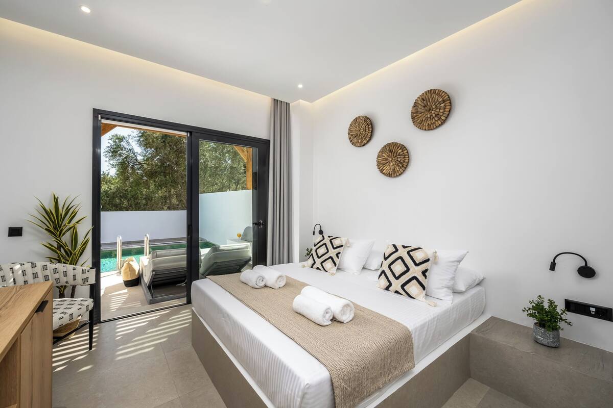 A modern hotel room with a large bed, a balcony with a view, and a minimalist decor.