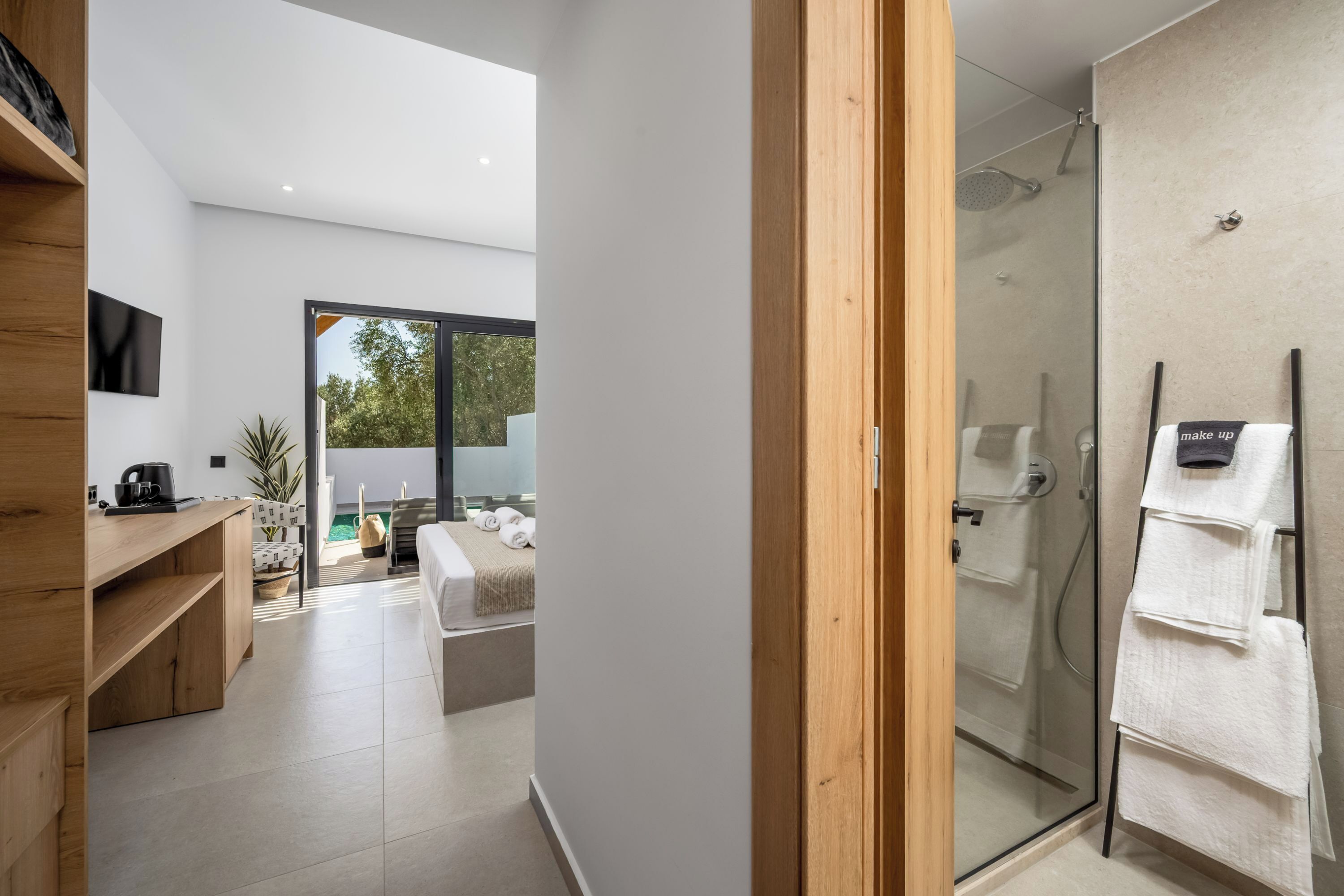 A modern bathroom with a glass shower enclosure, a wooden vanity, and a towel rack.