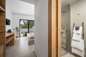 A modern bathroom with a glass shower enclosure, a wooden vanity, and a towel rack.