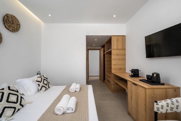 Une chambre d’hôtel moderne équipée d’un lit, d’un bureau, d’une télévision et d’un dressing.