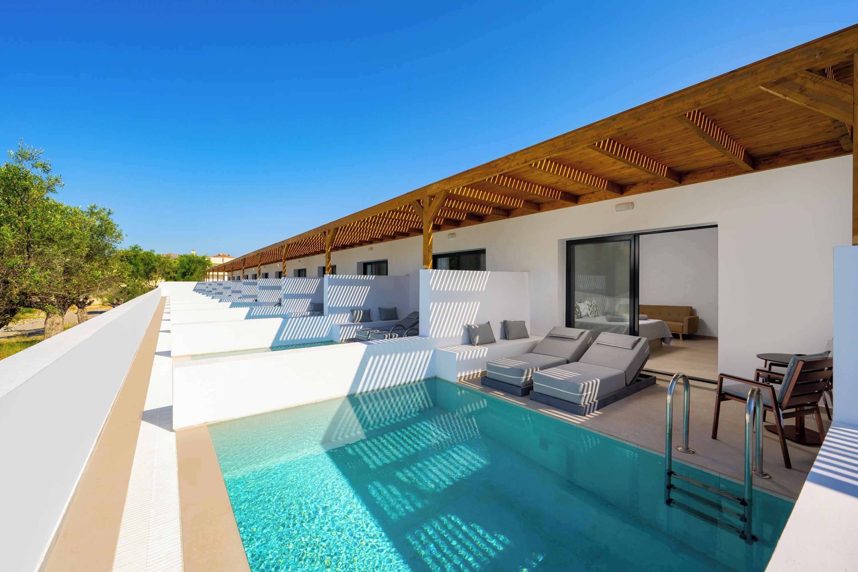 Ein moderner Poolbereich im Freien mit Liegestühlen und einer Holzpergola.