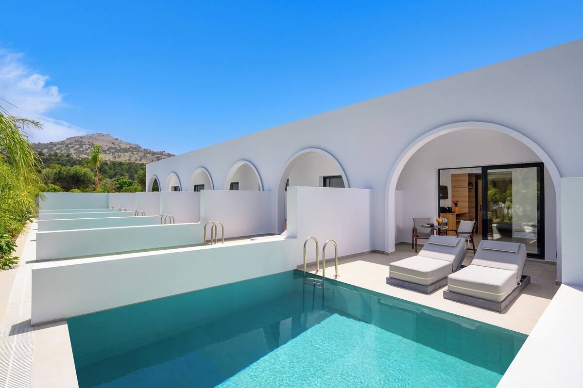 A modern pool area with clear blue water, white walls, and arched windows.