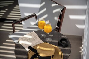 Ein Tisch mit einem Buch, zwei Orangensaftgläsern, einem Strohhut und einem sechseckigen Gegenstand.