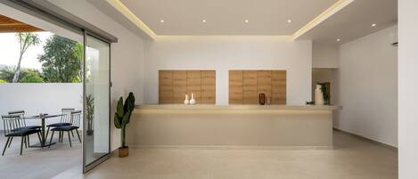 Una cocina moderna con una pared divisoria de vidrio, un comedor con sillas y una planta grande en maceta.