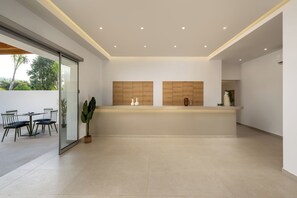 Una cocina moderna con una pared divisoria de vidrio, un comedor con sillas y una planta grande en maceta.