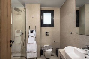 Une salle de bain moderne avec une douche à parois de verre, des toilettes, un lavabo et une fenêtre.