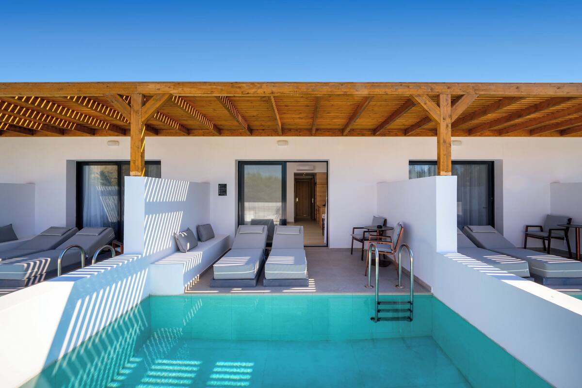 A modern pool area with lounge chairs and a covered seating area.
