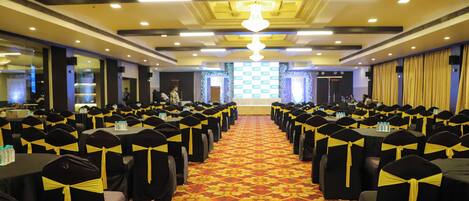 A conference room with rows of tables and chairs, a patterned carpet, and a chandelier.