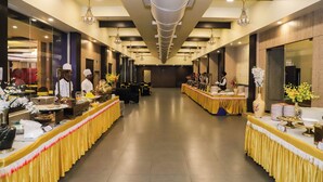 Un salón de banquetes con mesas largas, candelabros y un diseño moderno en el techo.