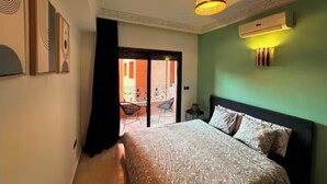 Ein Schlafzimmer mit einem Bett, einer Deckenleuchte, einer Klimaanlage und Blick auf einen Balkon.