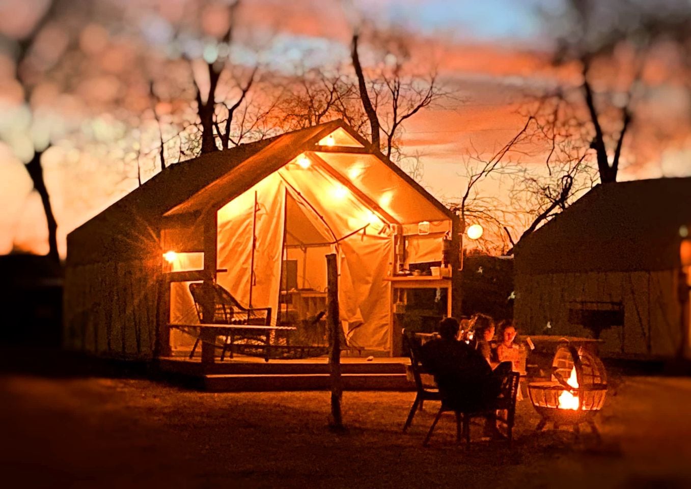 A tented accommodation with a dining area and a fire pit.