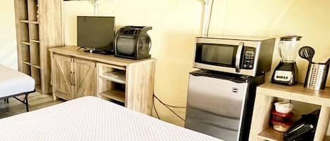Un hébergement sous tente comprenant un lit, un coin cuisine et une petite table.