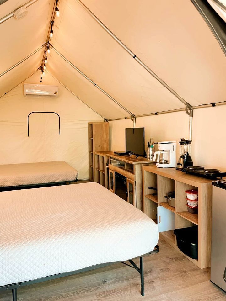 Una carpa con dos camas, una kitchenette y una mesita.
